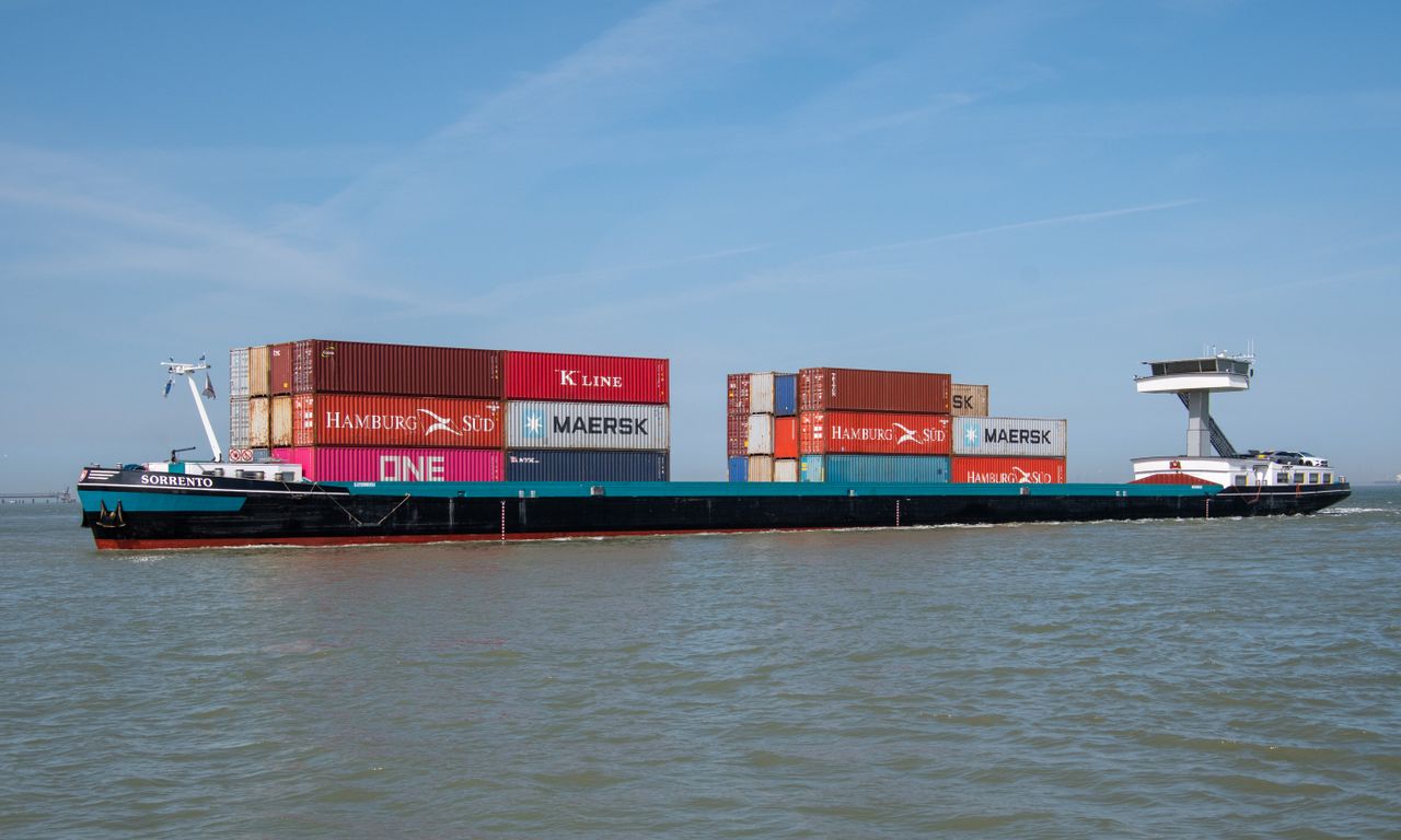 A cargo ship carrying various branded containers across the ocean on a clear day.